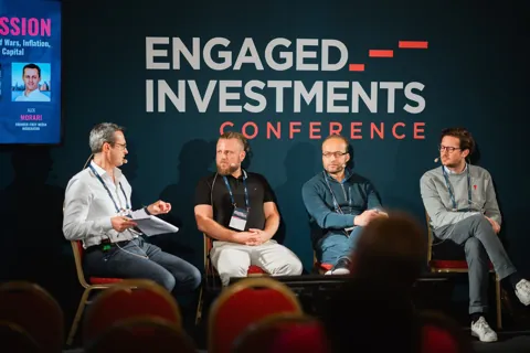 Alexander Morari moderating a panel while the screen credits him as moderator, Engaged Investments 2023 in Prague.