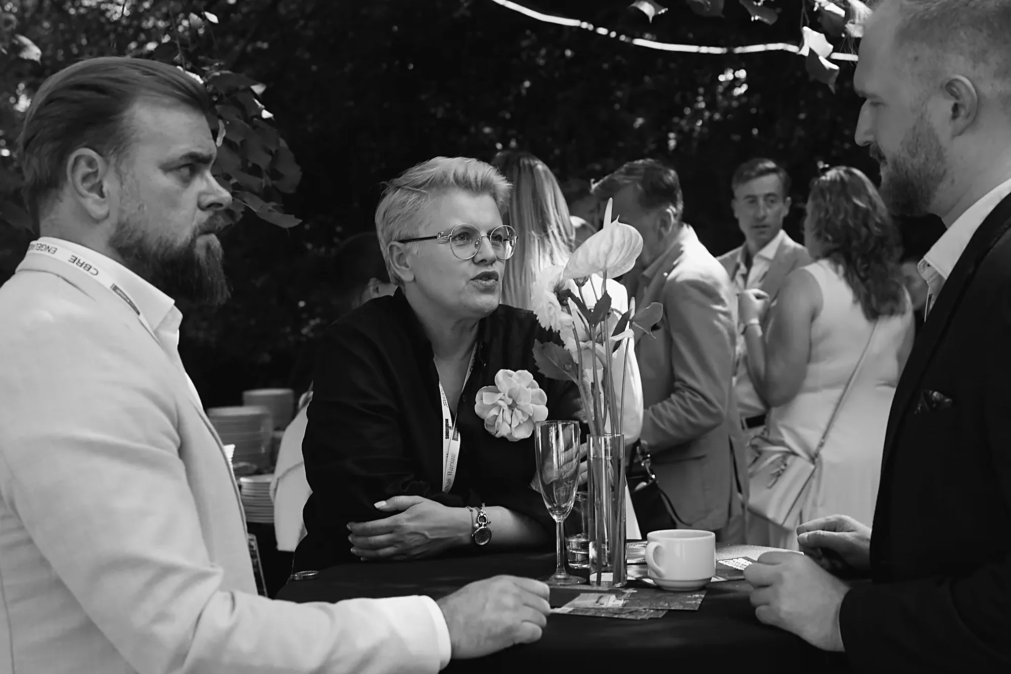 Three guests talking across a cocktail table in the garden at Mid-Summer Night 2026