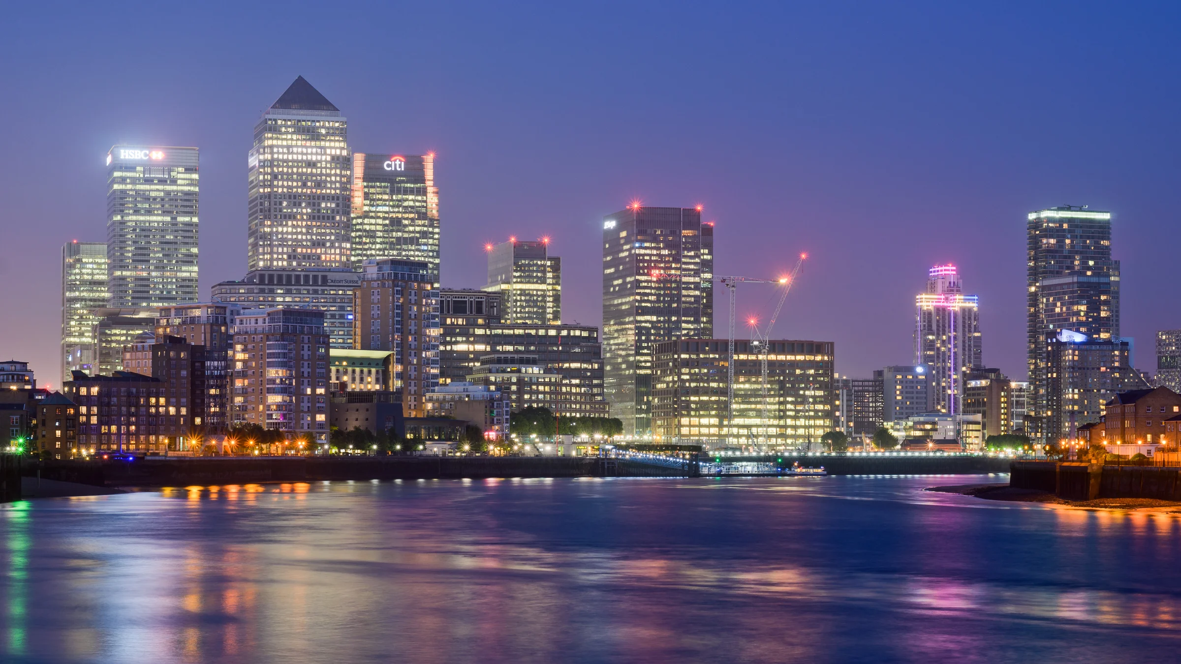 Canary Wharf office towers across the Thames at dusk, a London district where Gulf investors buy offices