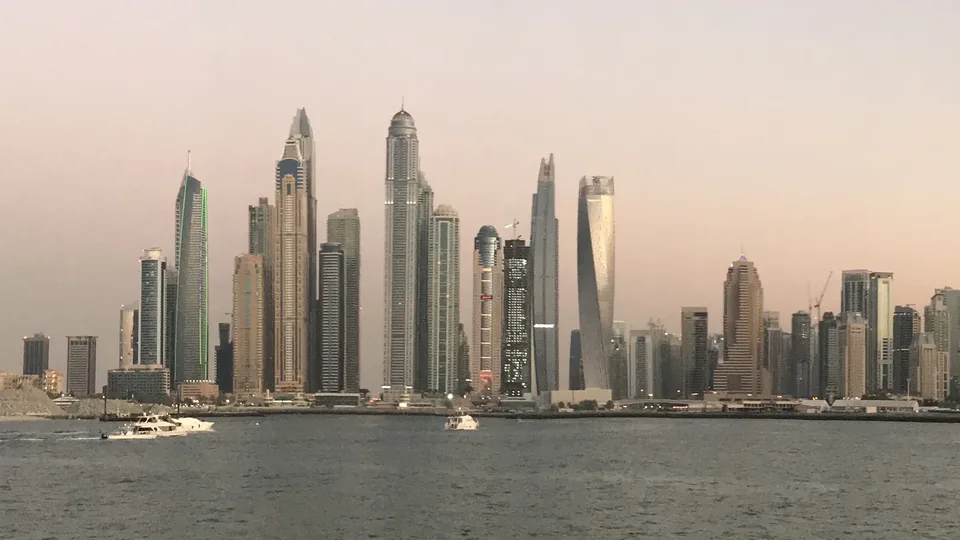 Dubai Marina towers at dusk across open water, the skyline of a city that private wealth and new firms are moving to