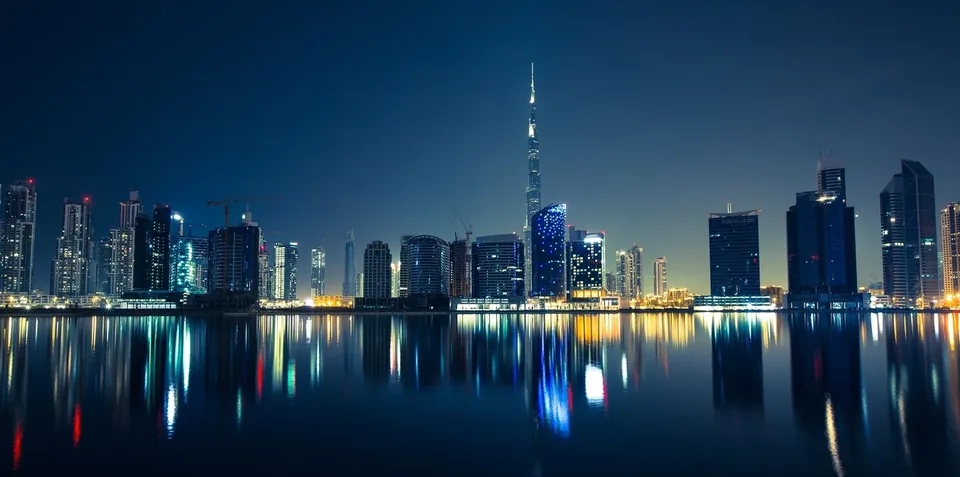 Dubai business district skyline at night with the Burj Khalifa, reflected in the water, the key visual of Dubai Office Summit